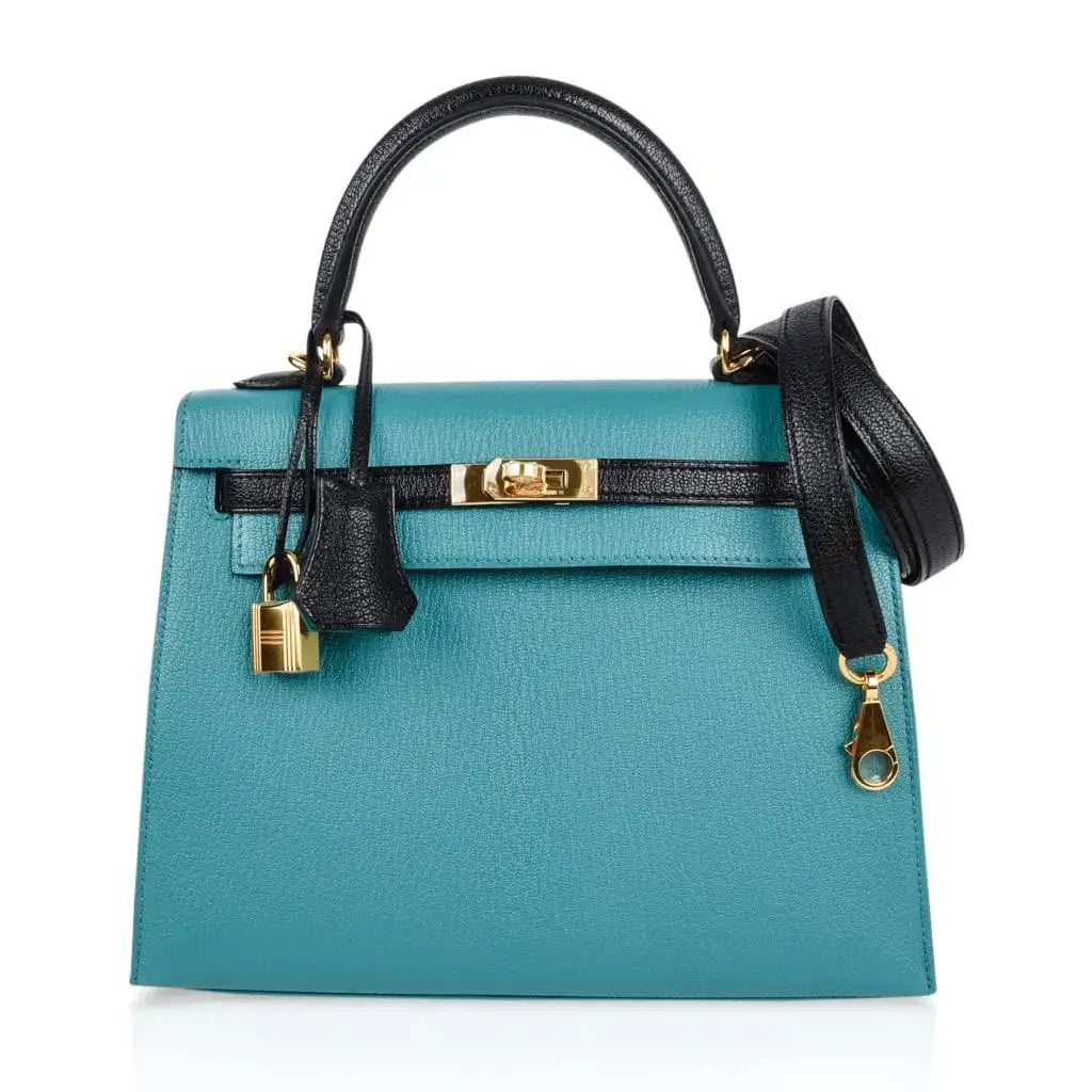 Model carrying Hermès Kelly 25 handbag in Blue with gold hardware.